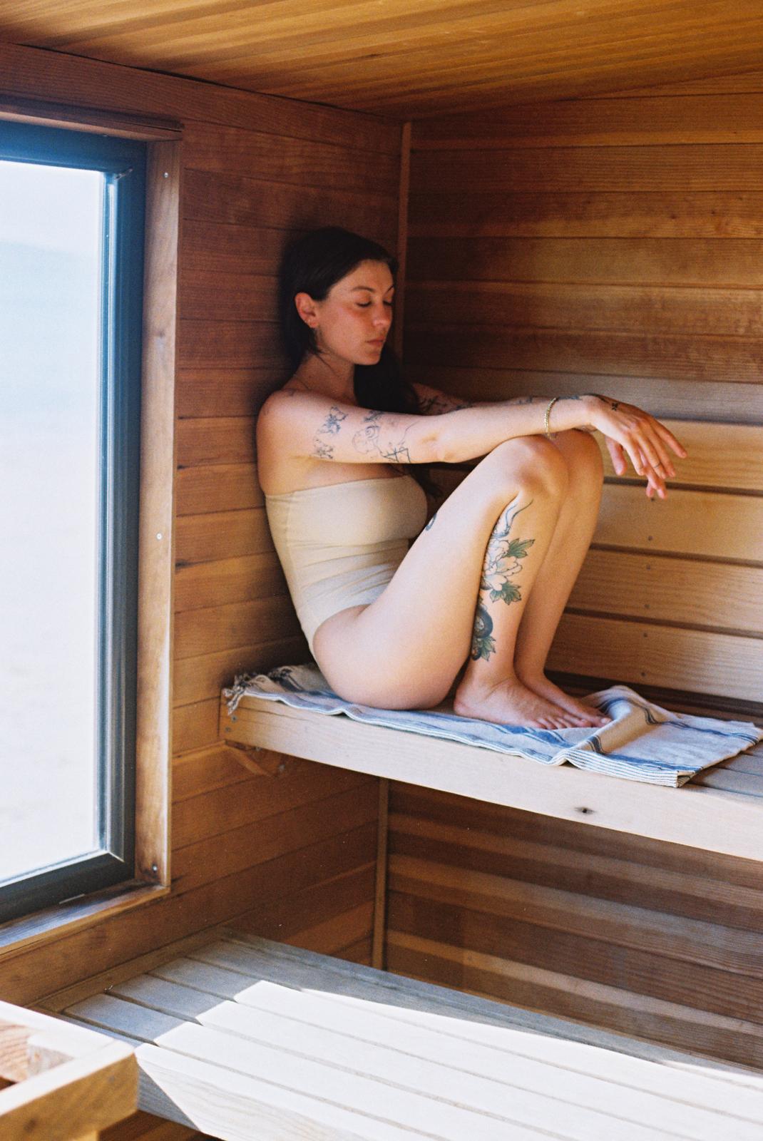 Guest relaxing on the timber bench beside the sauna window